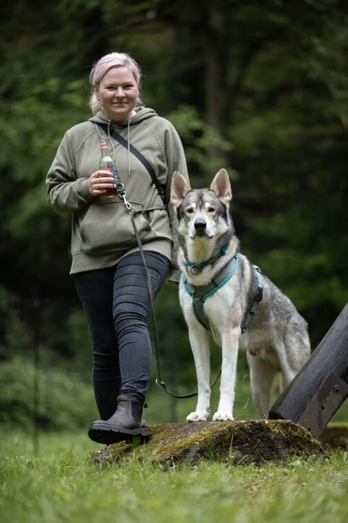 Nadine und Wolfalike Genos stehen nebeneinander auf Gras vor einem Wald